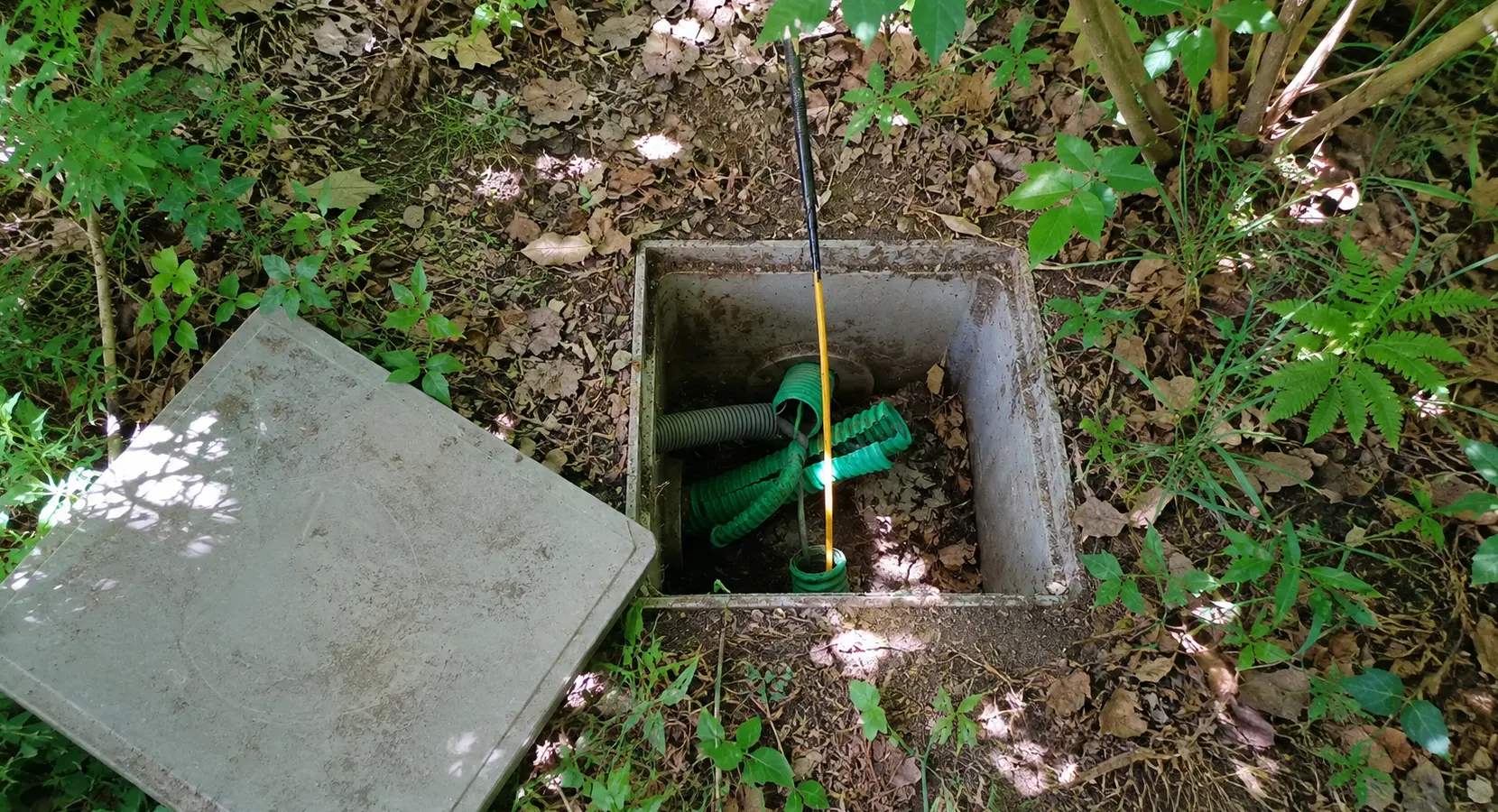 Regard télécom privé enterré dans un jardin avec fourreaux et aiguille de tirage